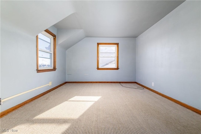 additional living space with carpet flooring, vaulted ceiling, plenty of natural light, and baseboards