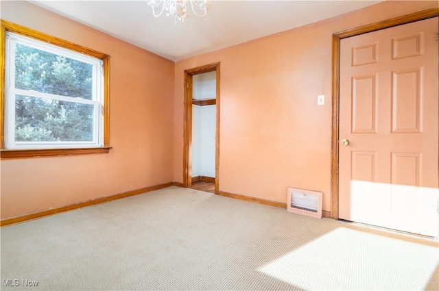 unfurnished bedroom featuring baseboards, a notable chandelier, and carpet flooring