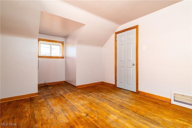 additional living space featuring visible vents, wood-type flooring, baseboards, and vaulted ceiling