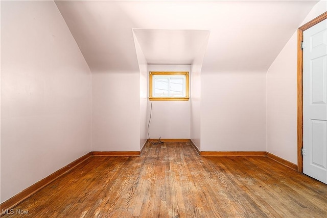 additional living space featuring baseboards and wood-type flooring