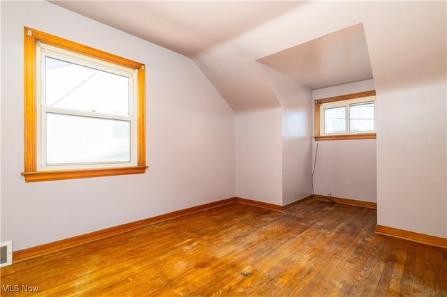 bonus room featuring hardwood / wood-style flooring, visible vents, baseboards, and vaulted ceiling