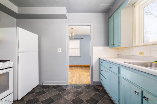 kitchen featuring blue cabinets, white appliances, tasteful backsplash, and light countertops