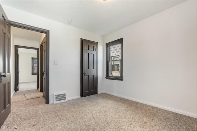 unfurnished bedroom with visible vents, baseboards, and carpet