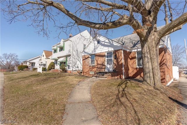 view of front of property with brick siding, a residential view, and a front lawn