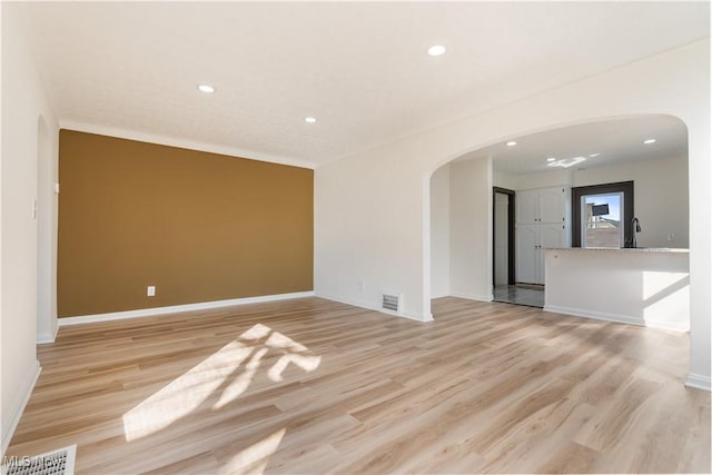 spare room with arched walkways, visible vents, recessed lighting, and light wood-type flooring