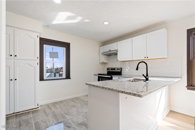 kitchen with under cabinet range hood, stainless steel electric range, white cabinetry, and a sink