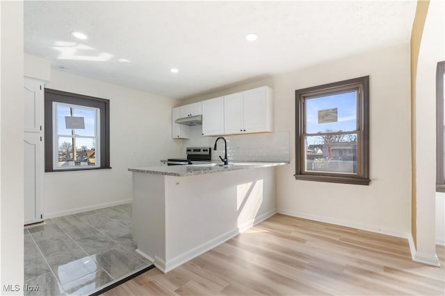 kitchen with stainless steel electric range oven, white cabinets, a healthy amount of sunlight, and under cabinet range hood