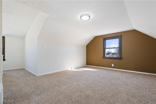 additional living space featuring baseboards, carpet floors, a textured ceiling, and vaulted ceiling