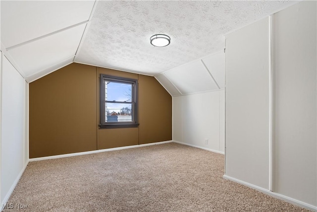 additional living space featuring baseboards, lofted ceiling, a textured ceiling, and carpet