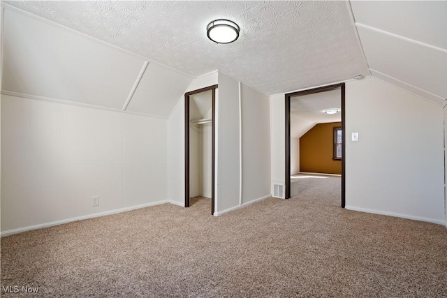 bonus room with carpet floors, a textured ceiling, and vaulted ceiling