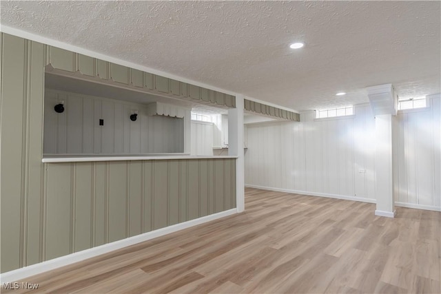 below grade area featuring a textured ceiling, baseboards, and wood finished floors