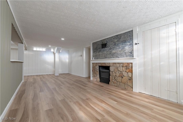 unfurnished living room featuring a stone fireplace, a textured ceiling, visible vents, and wood finished floors