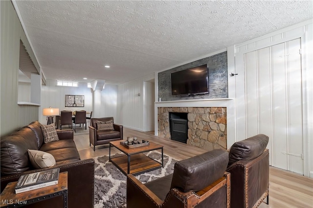 living area featuring light wood-style flooring, a fireplace, and a textured ceiling