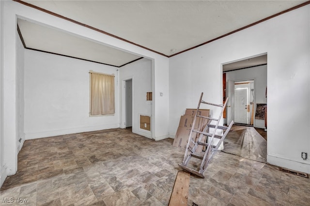 unfurnished room featuring stone finish flooring, baseboards, and ornamental molding