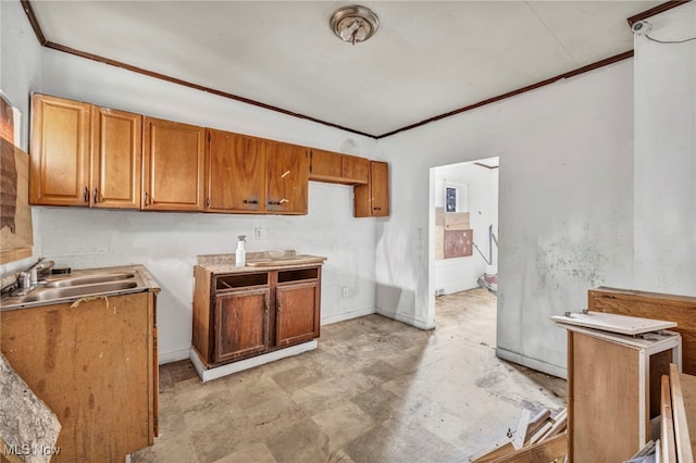 kitchen featuring a sink, baseboards, brown cabinets, and ornamental molding