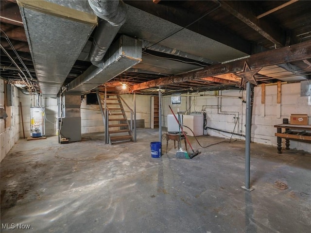 unfinished below grade area featuring electric panel, heating unit, washing machine and dryer, gas water heater, and stairs