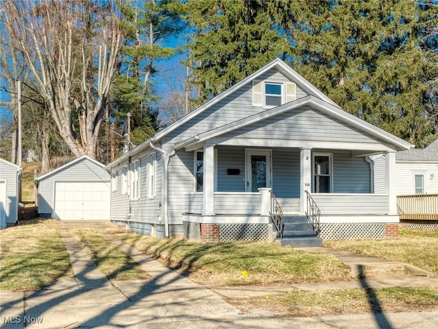 bungalow-style house with an outbuilding, covered porch, concrete driveway, a front lawn, and a detached garage