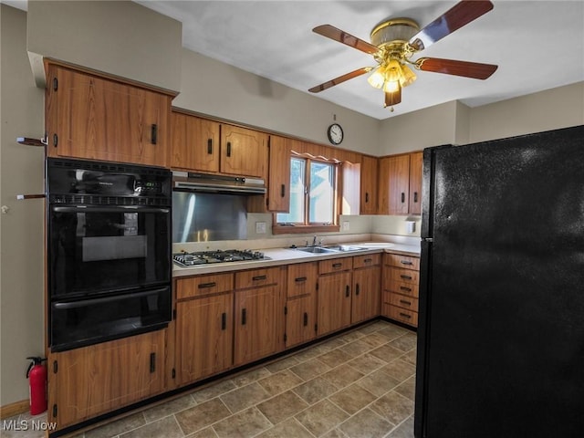 kitchen featuring a warming drawer, black appliances, under cabinet range hood, a sink, and light countertops