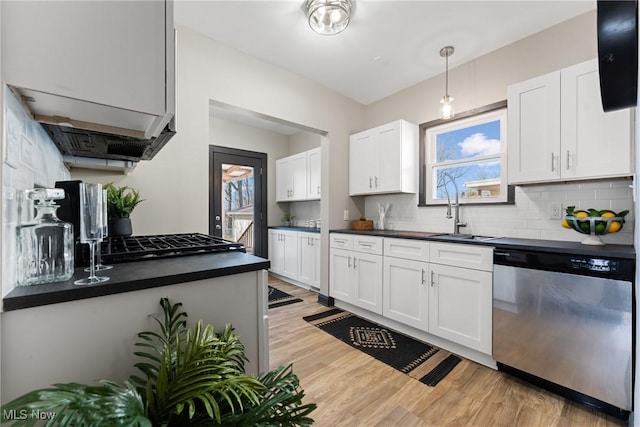 kitchen with dark countertops, light wood finished floors, dishwasher, decorative backsplash, and a sink