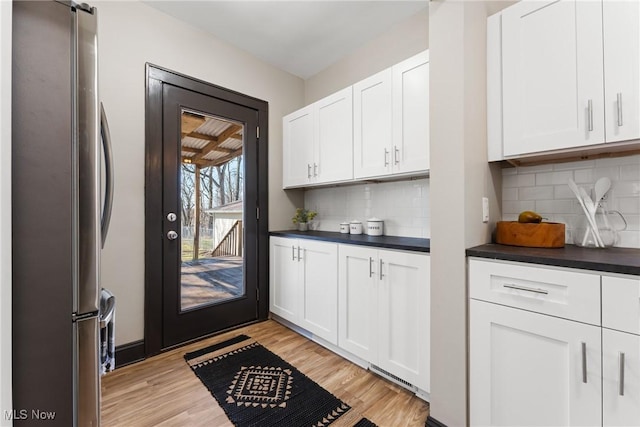 kitchen featuring dark countertops, white cabinets, light wood-style flooring, and freestanding refrigerator