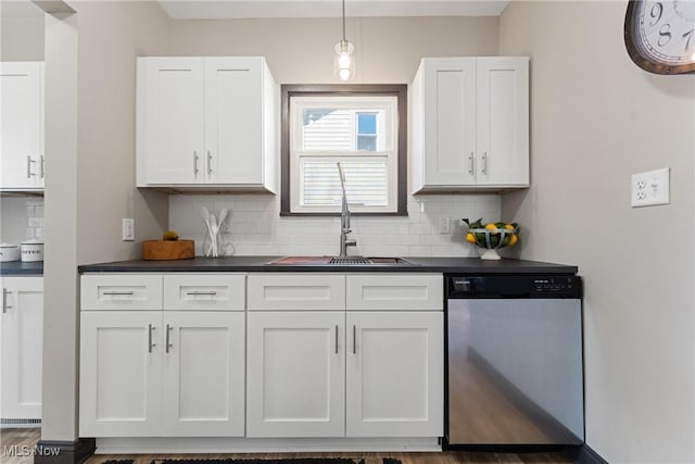 kitchen with a sink, stainless steel dishwasher, dark countertops, and white cabinets