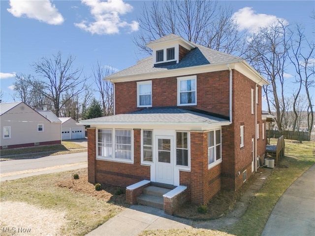 american foursquare style home featuring entry steps, an outbuilding, and brick siding