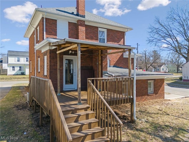 back of property featuring brick siding, a chimney, and a shingled roof