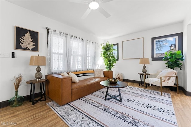 living room featuring light wood-type flooring, baseboards, and a ceiling fan