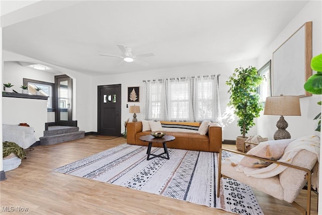 living room featuring arched walkways, ceiling fan, and wood finished floors