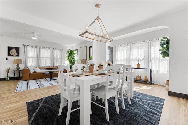 dining room with ceiling fan with notable chandelier and wood finished floors