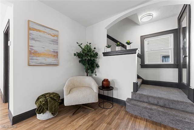 sitting room featuring stairs, baseboards, and wood finished floors