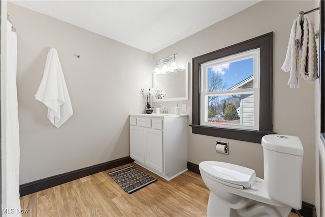 full bathroom featuring baseboards, toilet, wood finished floors, and vanity