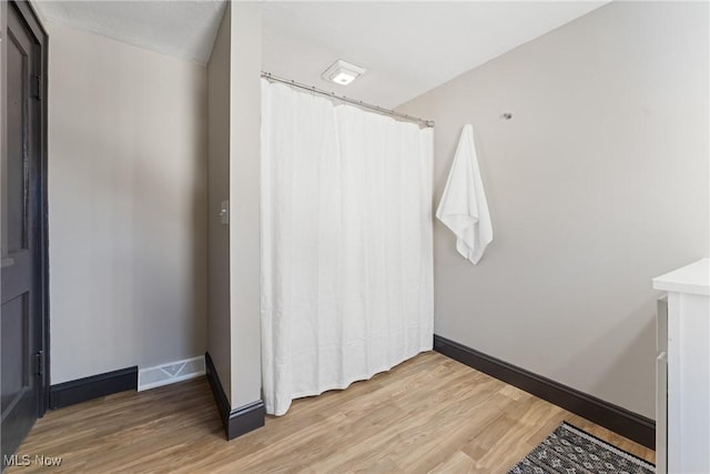 bathroom with baseboards, a shower with curtain, and wood finished floors