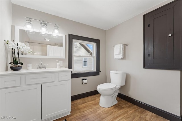 bathroom featuring vanity, wood finished floors, baseboards, curtained shower, and toilet