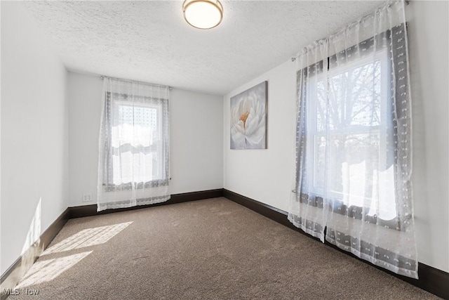 carpeted empty room with baseboards and a textured ceiling