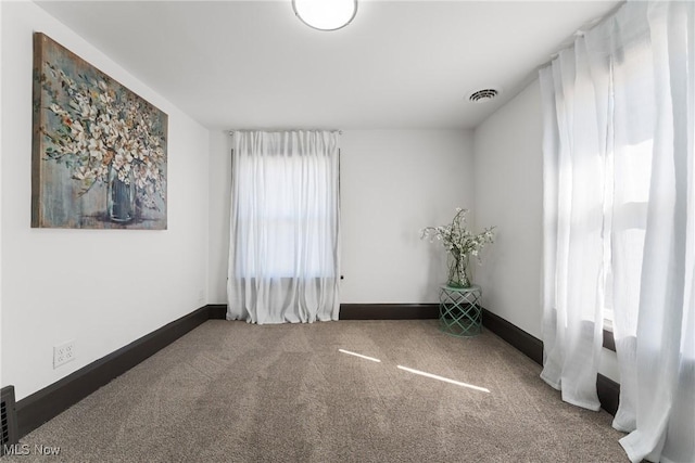 spare room with visible vents, carpet floors, and baseboards