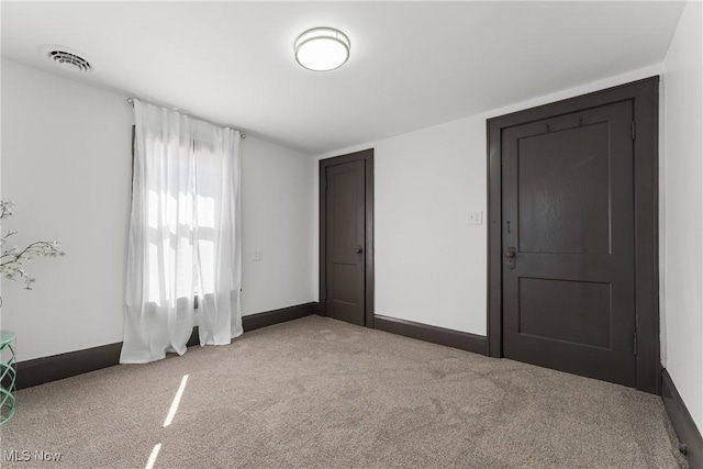 unfurnished room featuring light carpet, visible vents, and baseboards