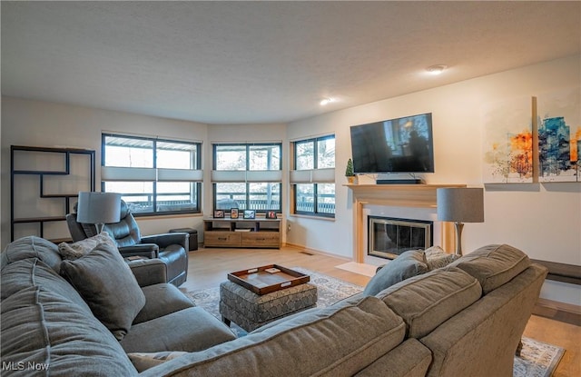 living room with a fireplace with flush hearth, baseboards, and light wood finished floors