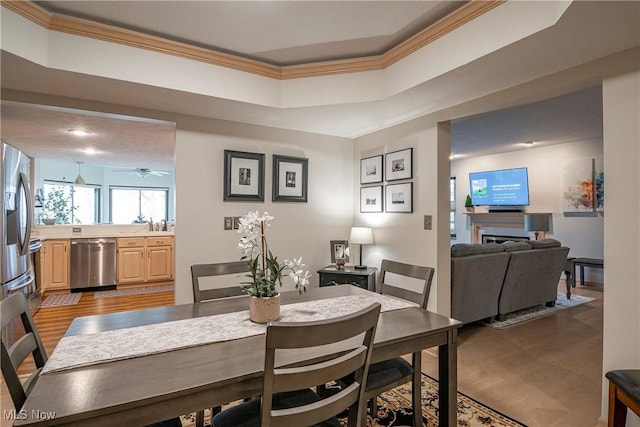 dining room with a fireplace, wood finished floors, and ornamental molding