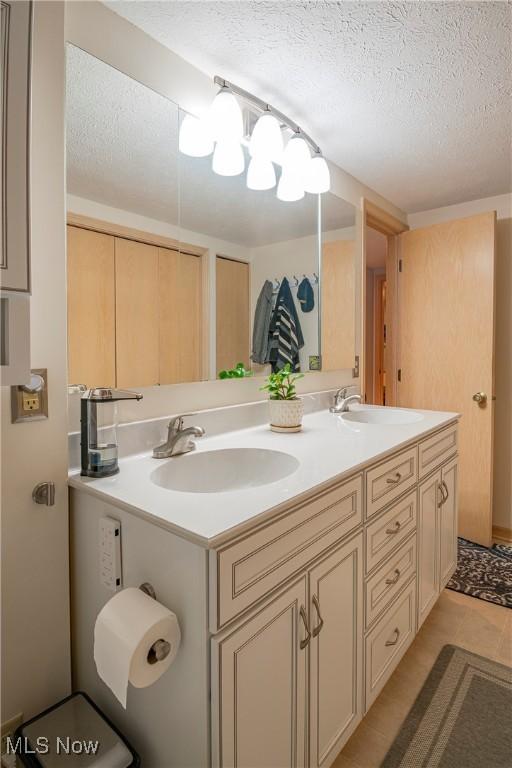 full bathroom featuring a textured ceiling, double vanity, and a sink