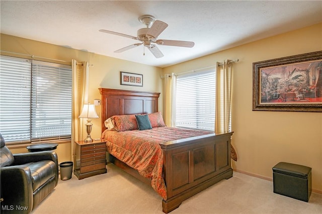 bedroom with light colored carpet, baseboards, and a ceiling fan