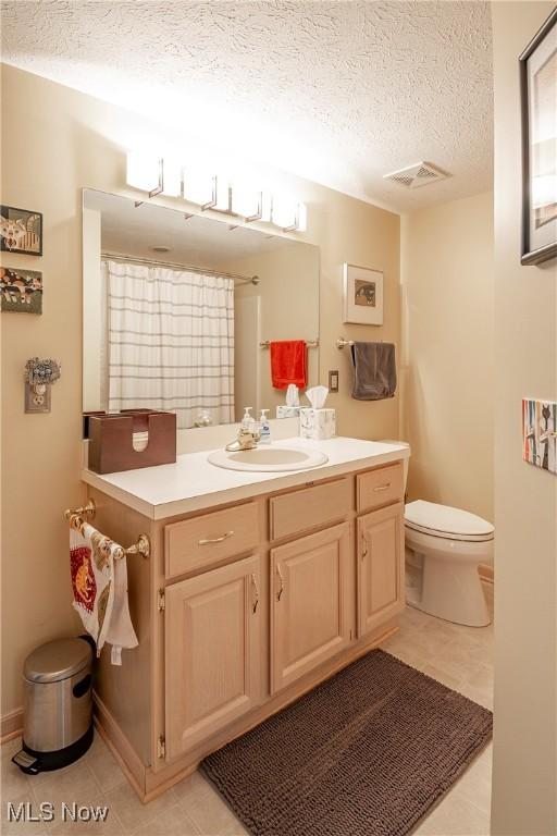 full bathroom featuring tile patterned floors, visible vents, toilet, a textured ceiling, and vanity