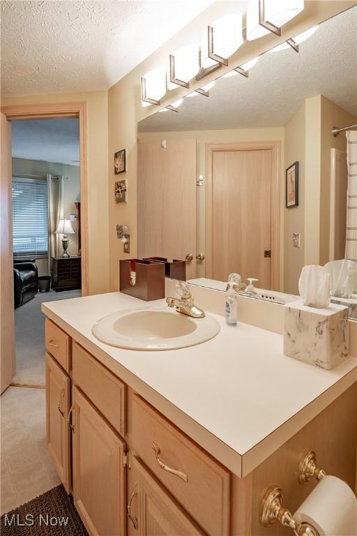 full bath with a textured ceiling and vanity