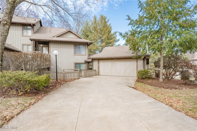 view of front of home with fence, driveway, and a shingled roof