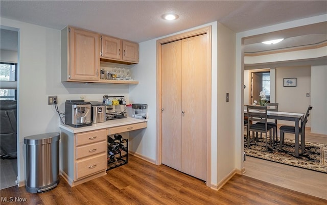 home office featuring baseboards, wood finished floors, and built in study area