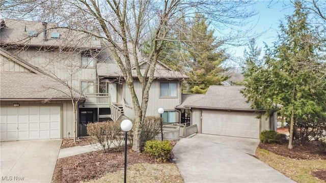 view of front of home featuring an attached garage, concrete driveway, stairs, and roof with shingles