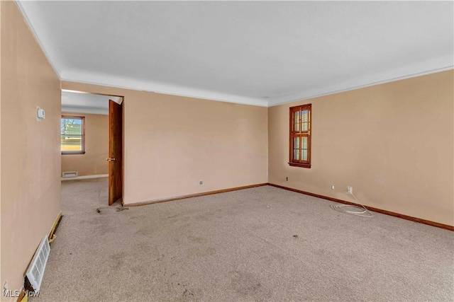 unfurnished room featuring visible vents, baseboards, carpet, and ornamental molding