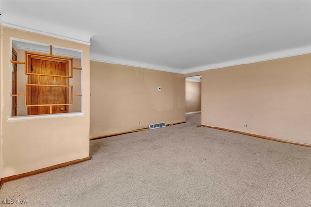 carpeted empty room with visible vents, baseboards, and crown molding