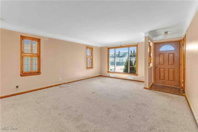 foyer entrance featuring carpet flooring, baseboards, and ornamental molding