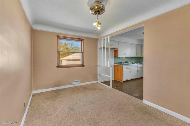 unfurnished room featuring visible vents, dark carpet, a textured ceiling, and baseboards